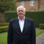 Portrait éditorial d'un acteur britannique distingué en blazer marine dans un jardin anglais traditionnel