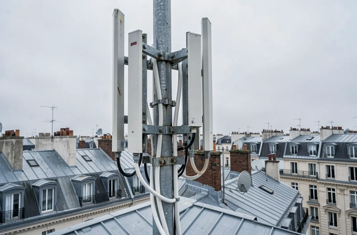 Antenne 5G installée sur un toit d'immeuble dans une ville française avec panorama urbain